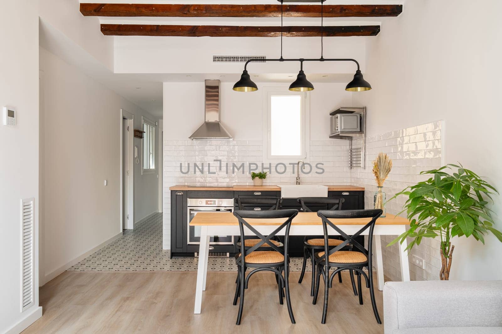 Minimalist kitchen zone with table and appliances in studio apartment. Area for cooking and dining with stylish furniture and equipment at home