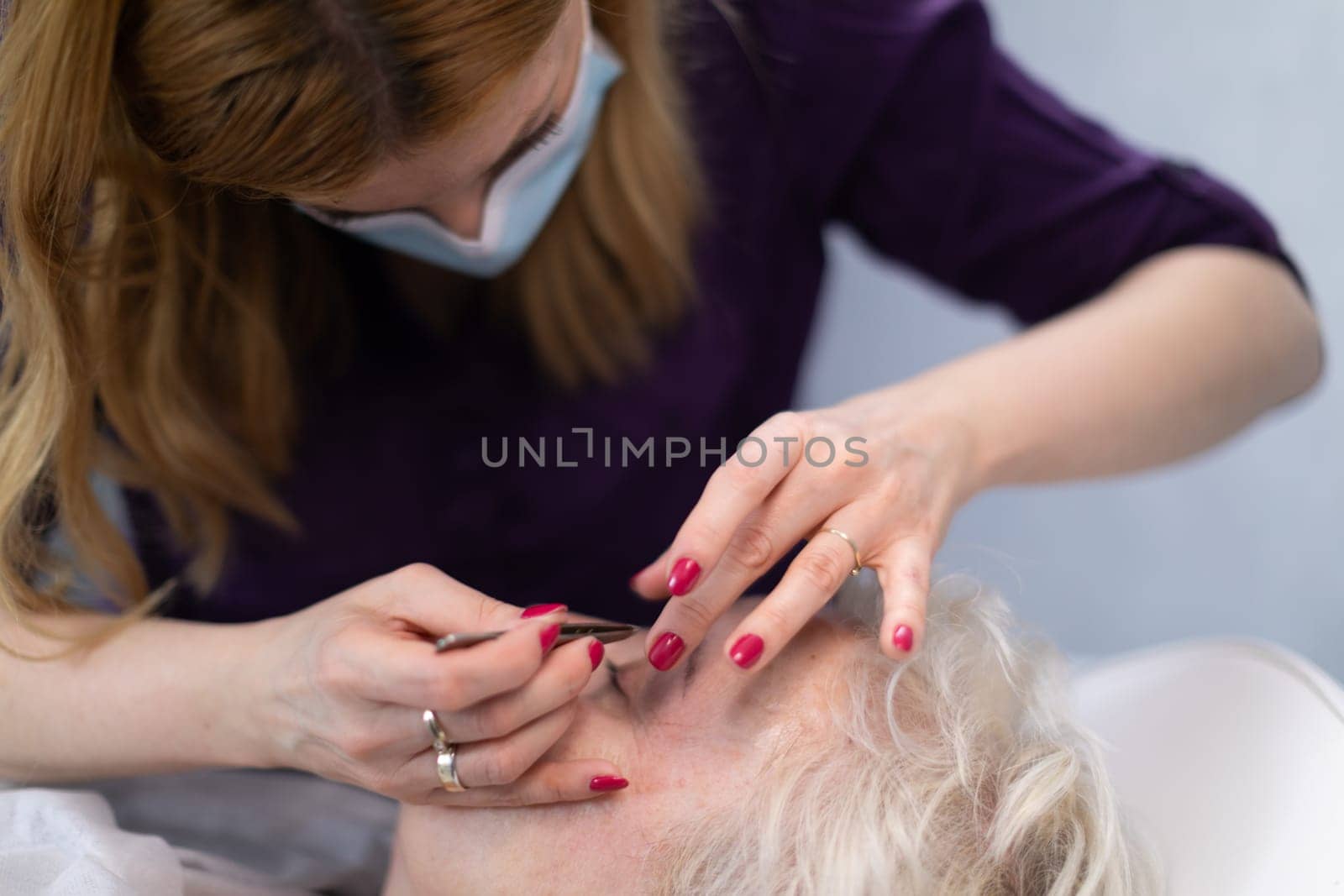 The beautician removes facial hair during her client's visit. by fotodrobik