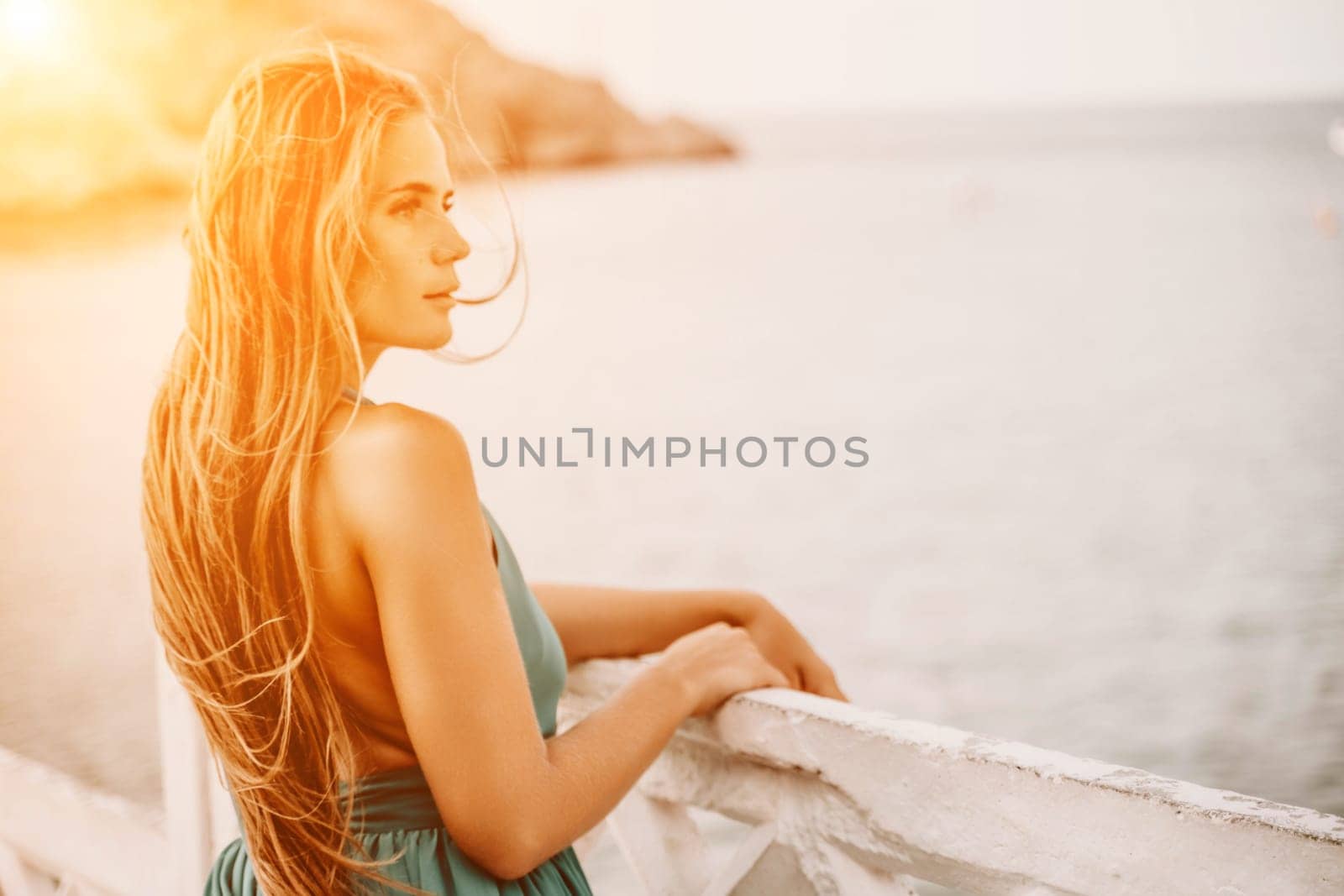 Woman sea trevel green dress. Side view a happy woman with long hair in a long mint dress posing on a beach with calm sea bokeh lights on sunny day. Girl on the nature on blue sky background