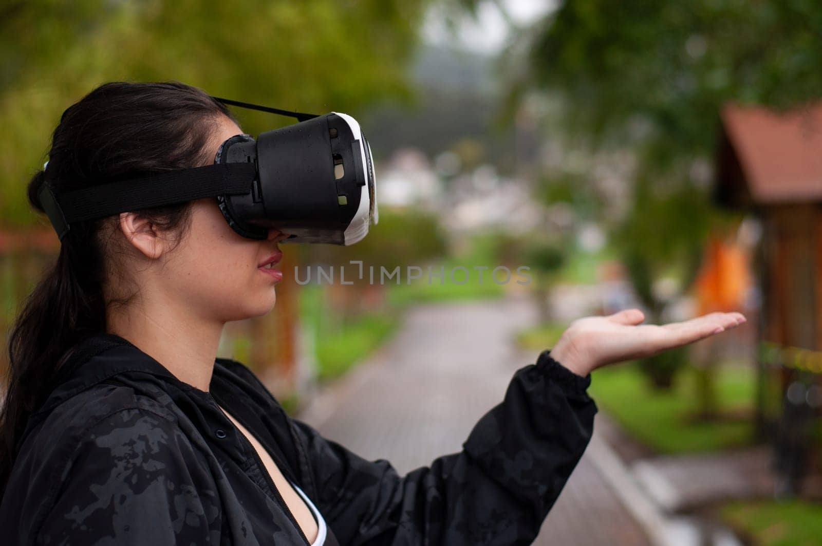 a girl from the future with augmented reality glasses or a black jacket with a raised hand in the shape of a copyspace tray. High quality photo