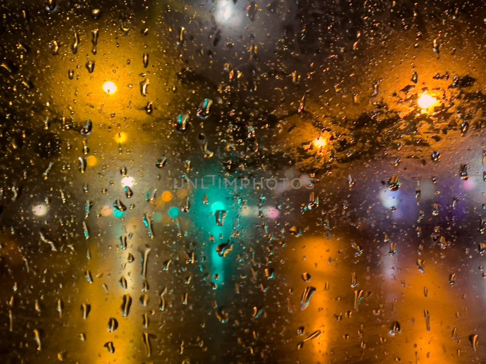 Rain bokeh road lights. Abstract shot of evening city traffic bokeh. Multicolored lights of the evening city and passing cars through a wet rainy window. by Matiunina