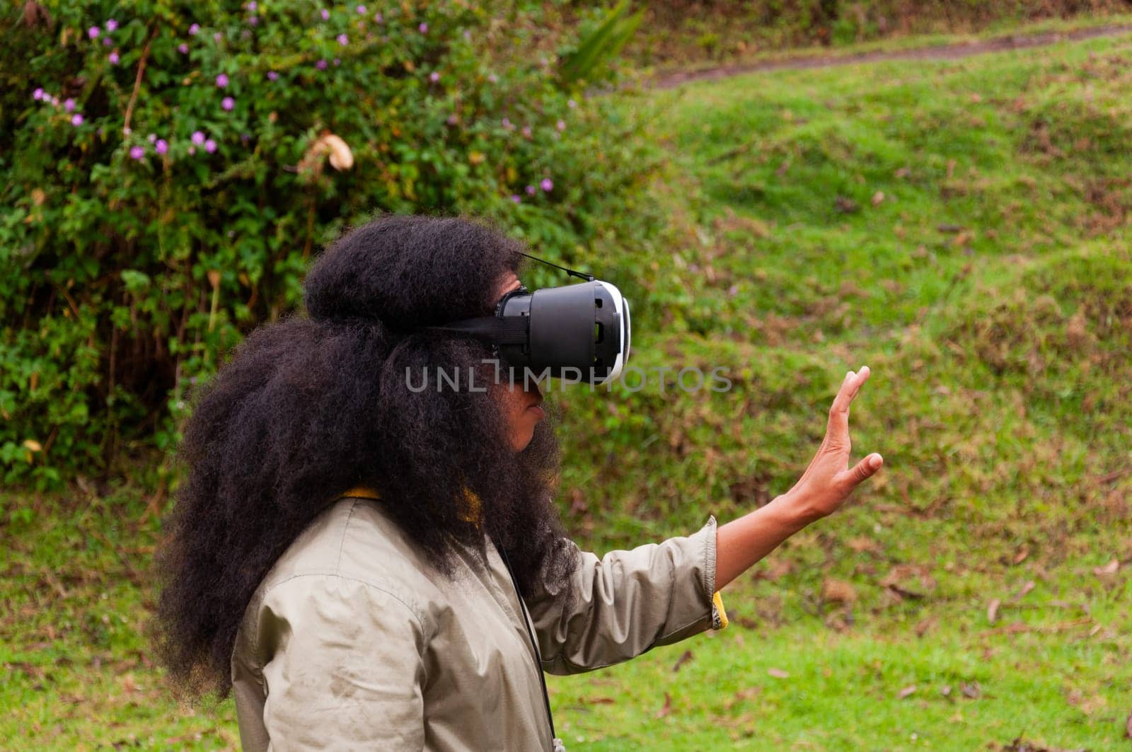 Afro-Ecuadorian girl with virtual reality goggles experiencing the third dimension in nature by Raulmartin