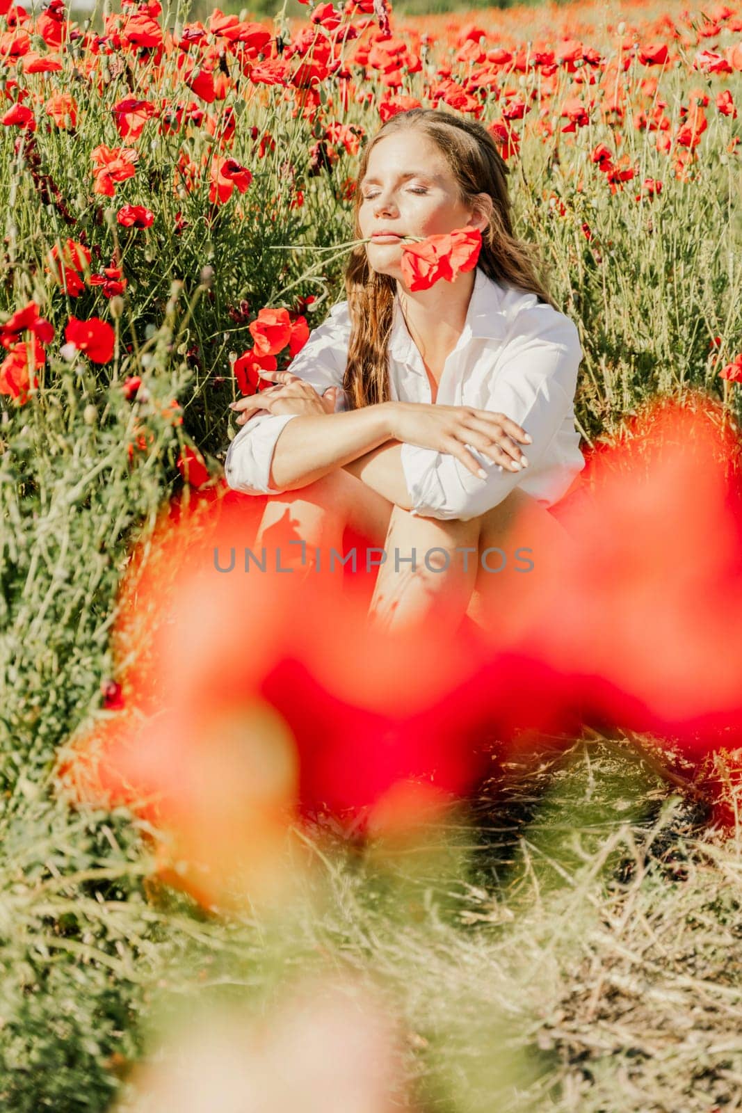Woman poppies field. Happy woman is resting in the rays of the sun sitting in the poppy field. by Matiunina