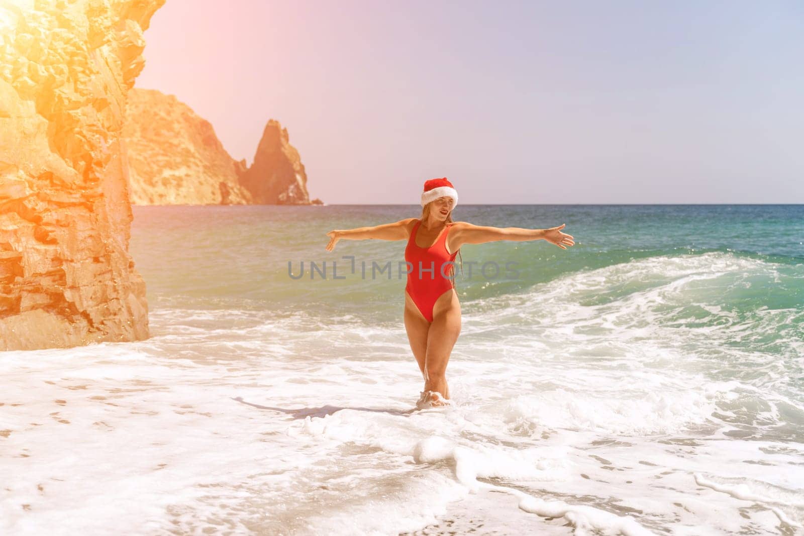 A woman in Santa hat on the seashore, dressed in a red swimsuit. New Year's celebration in a hot country. by Matiunina