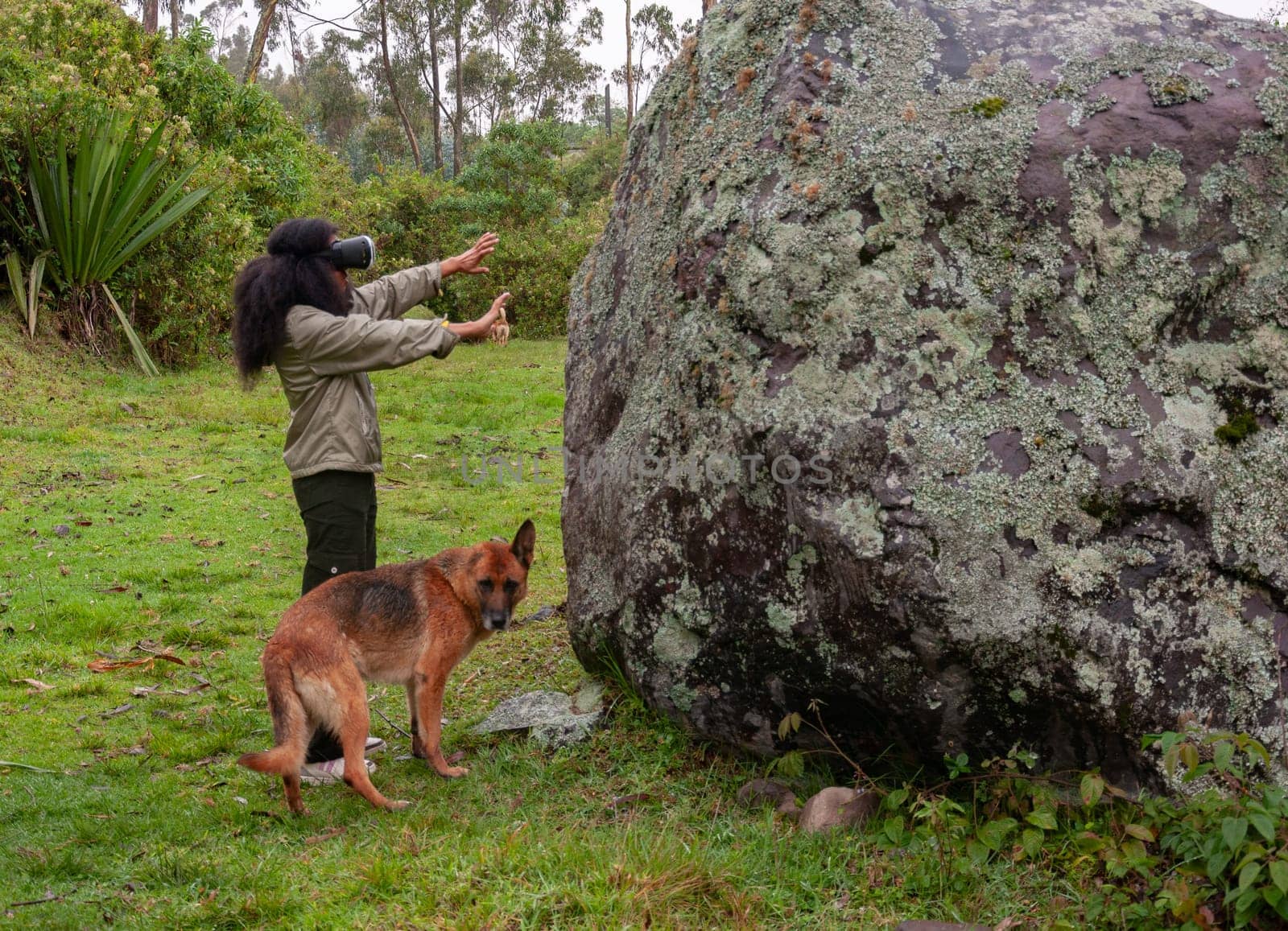 afro girl with augmented reality glasses getting information about a prehistoric stone thanks to advanced technology together with her earless dog. High quality photo