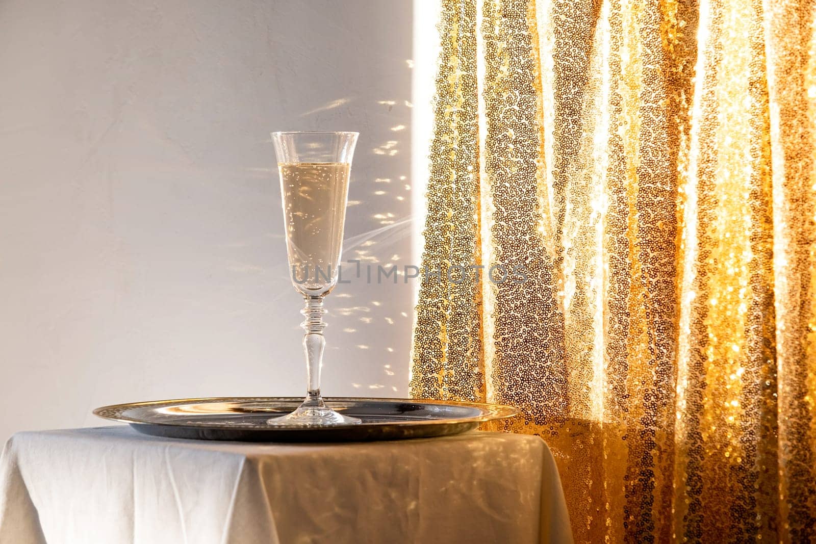 Champagne flutes in tray on table against gold sparkling background by Desperada