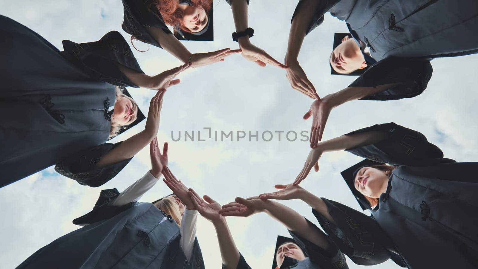 College graduates make a circle of their hands. by DovidPro