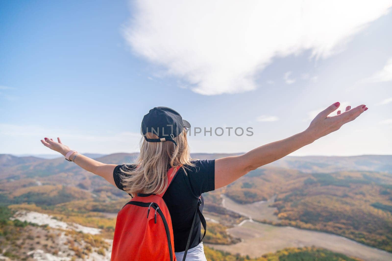 woman backpack on mountain peak looking in beautiful mountain valley in autumn. Landscape with sporty young woman, blu sky in fall. Hiking. Nature by Matiunina