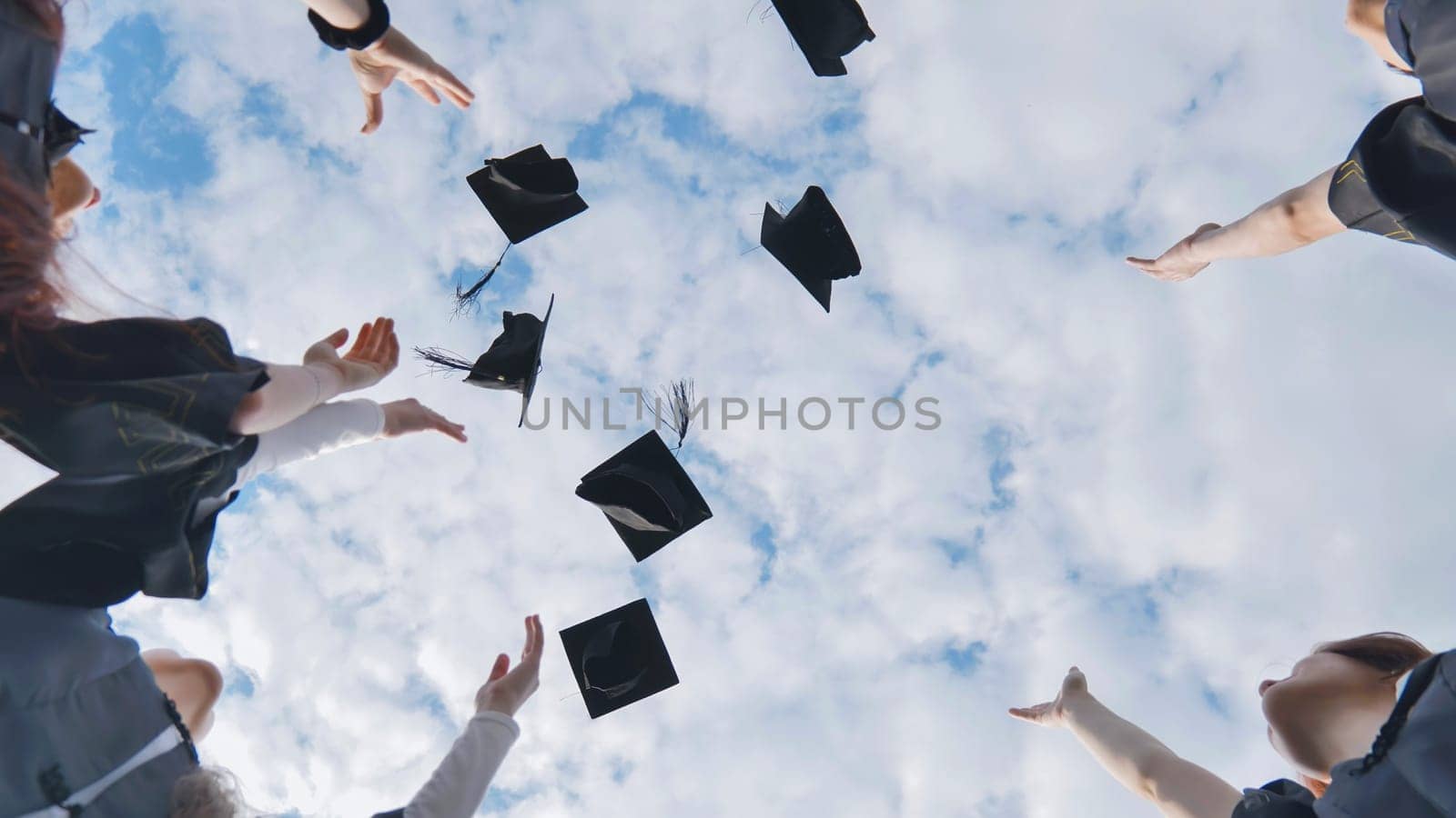 Silhouettes of Happy college graduates tossing their caps up at sunset.