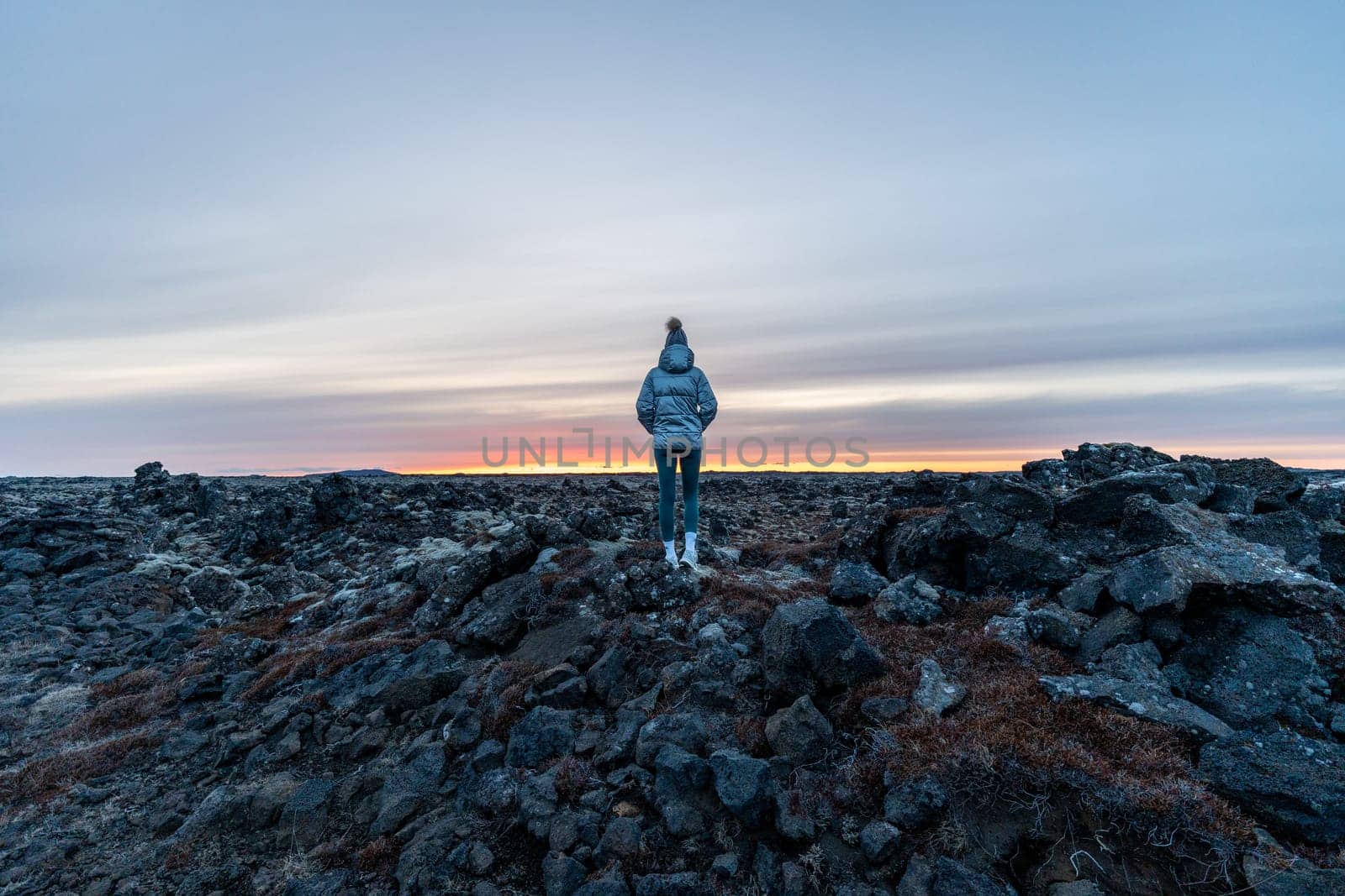 Woman posing in an ancient lava field watching sunset