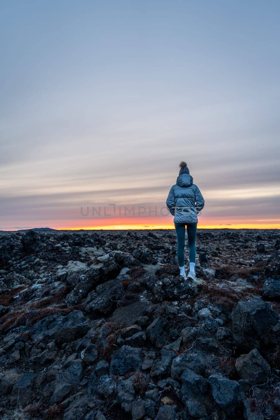 Woman posing in an ancient lava field watching sunset