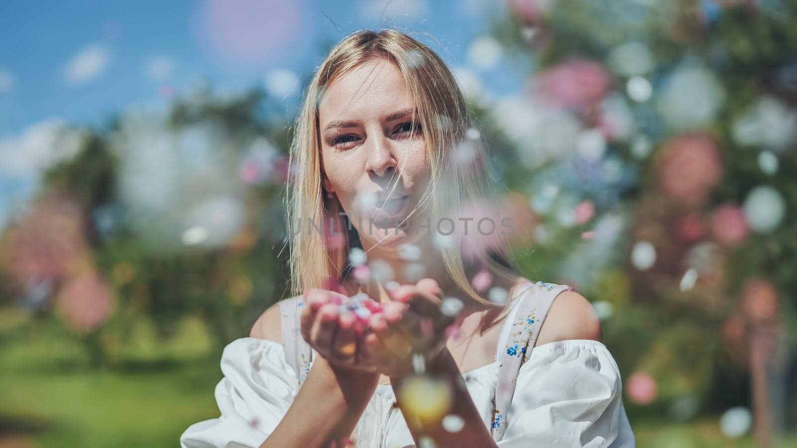 A girl blows a multi-coloured paper confetti out of her hands