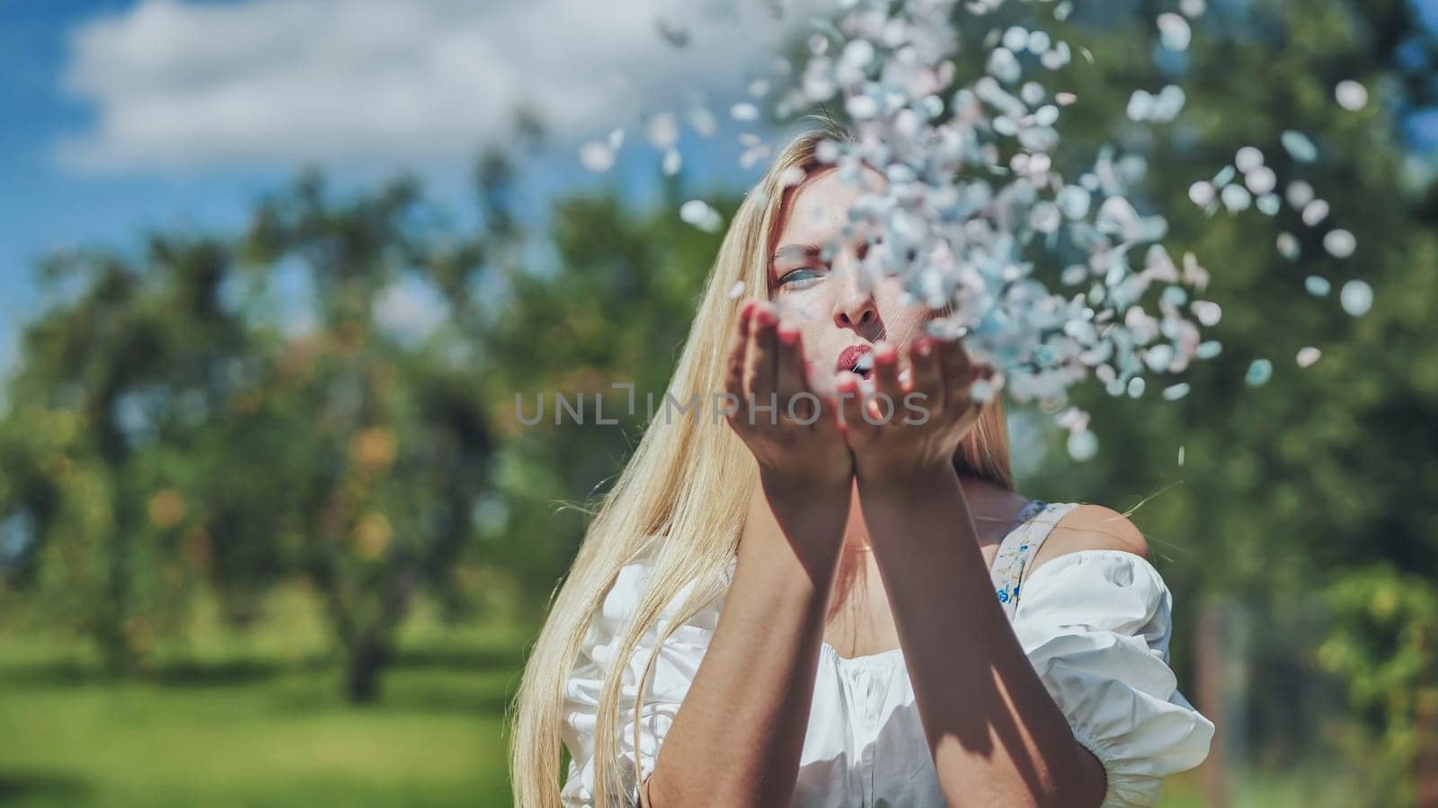 A girl blows a multi-coloured paper confetti out of her hands