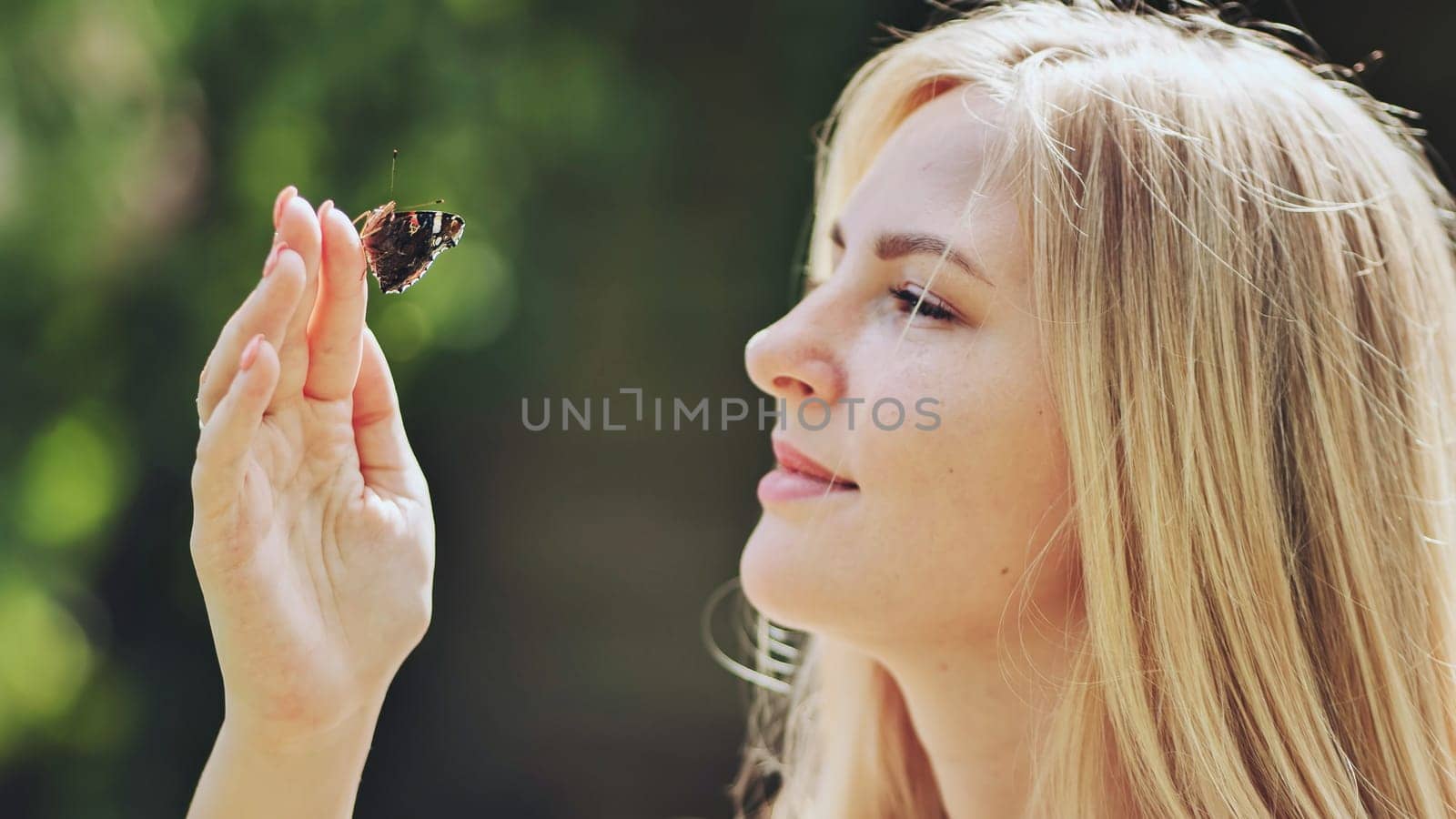 Young blonde girl with a butterfly on a summer afternoon