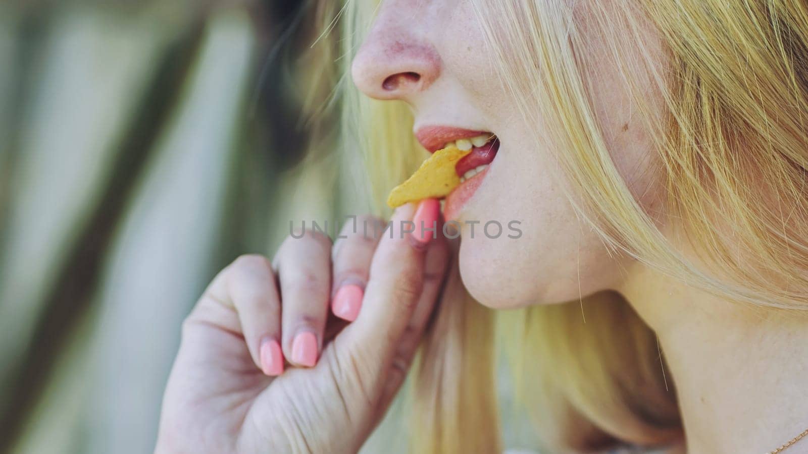 Blonde girl eating chips on the street