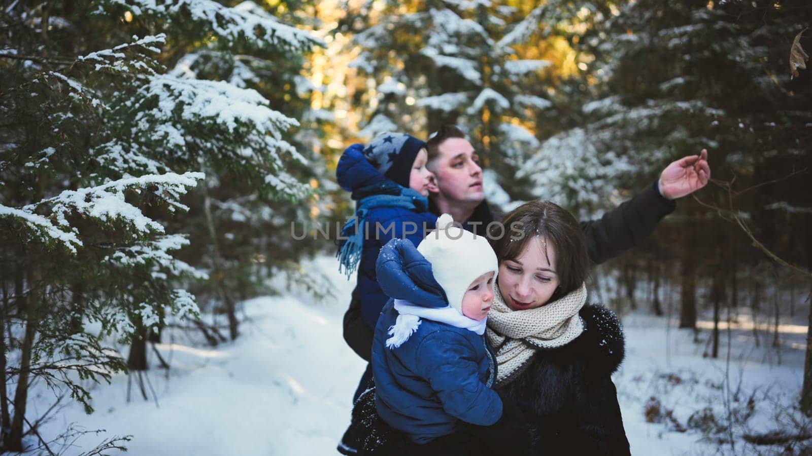 A young family is walking through a winter forest