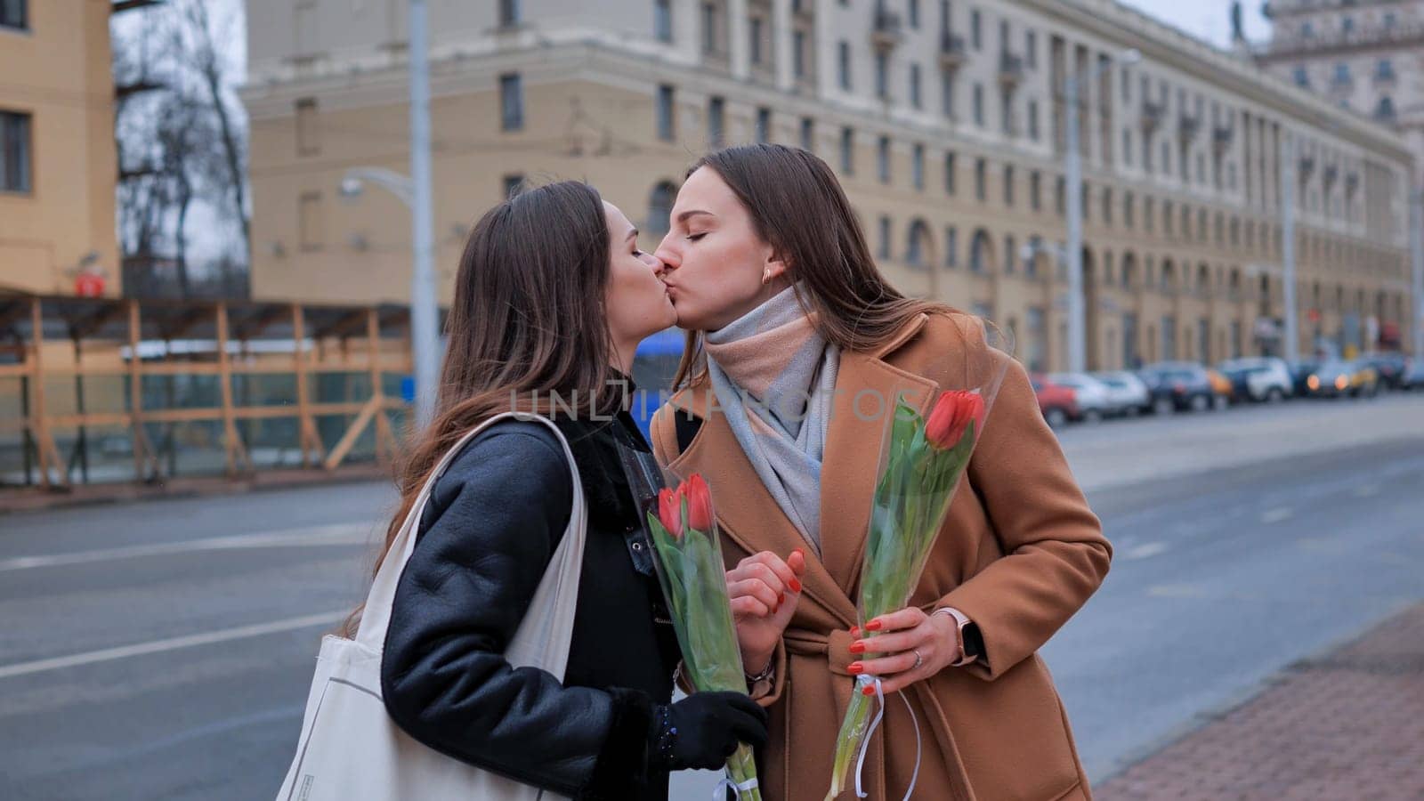 Two young women kissing each other on a city street