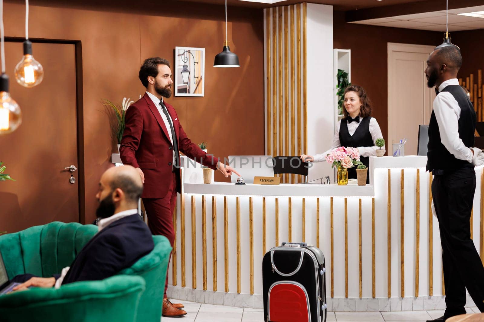 Front desk staff greets businessman with suitcase baggage, travelling on work trip and staying at luxury hotel. Formal person entering lobby to ask about room reservation, registration.