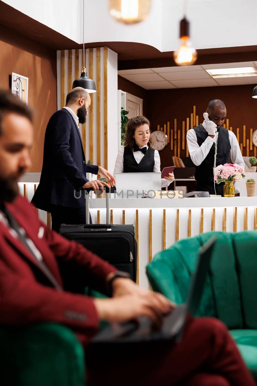 Traveling for work, businessman checking in at hotel reception desk with passport for room reservation confirmation. Guest giving id documents to front desk staff, identification services.