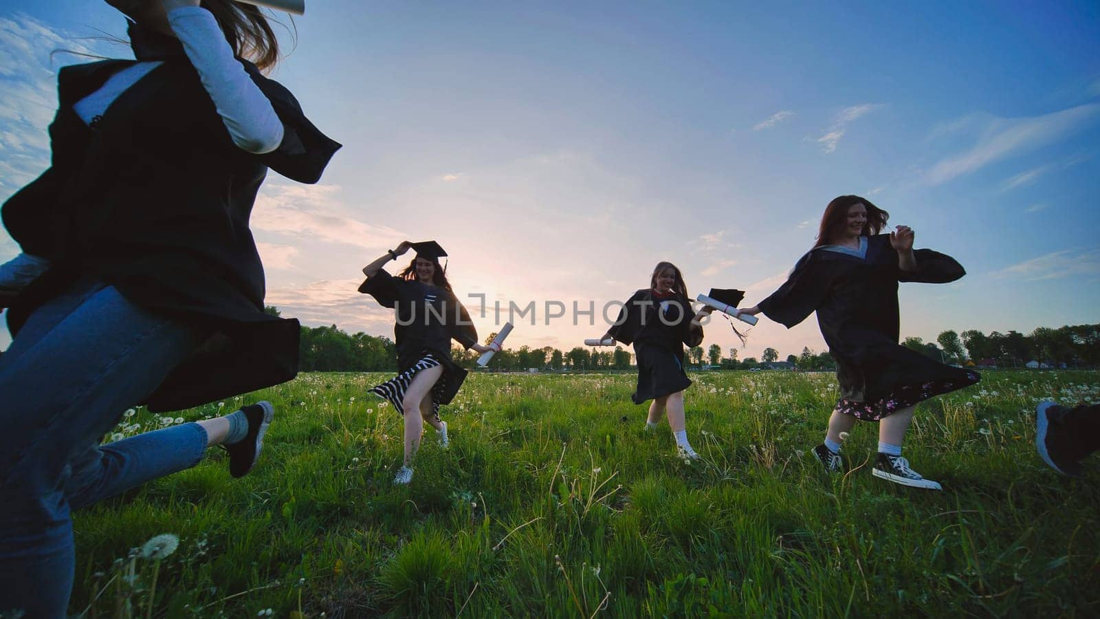 College graduates run at sunset in the evening. by DovidPro
