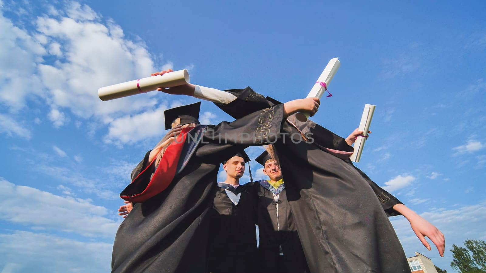 College graduates embrace in a circle. by DovidPro