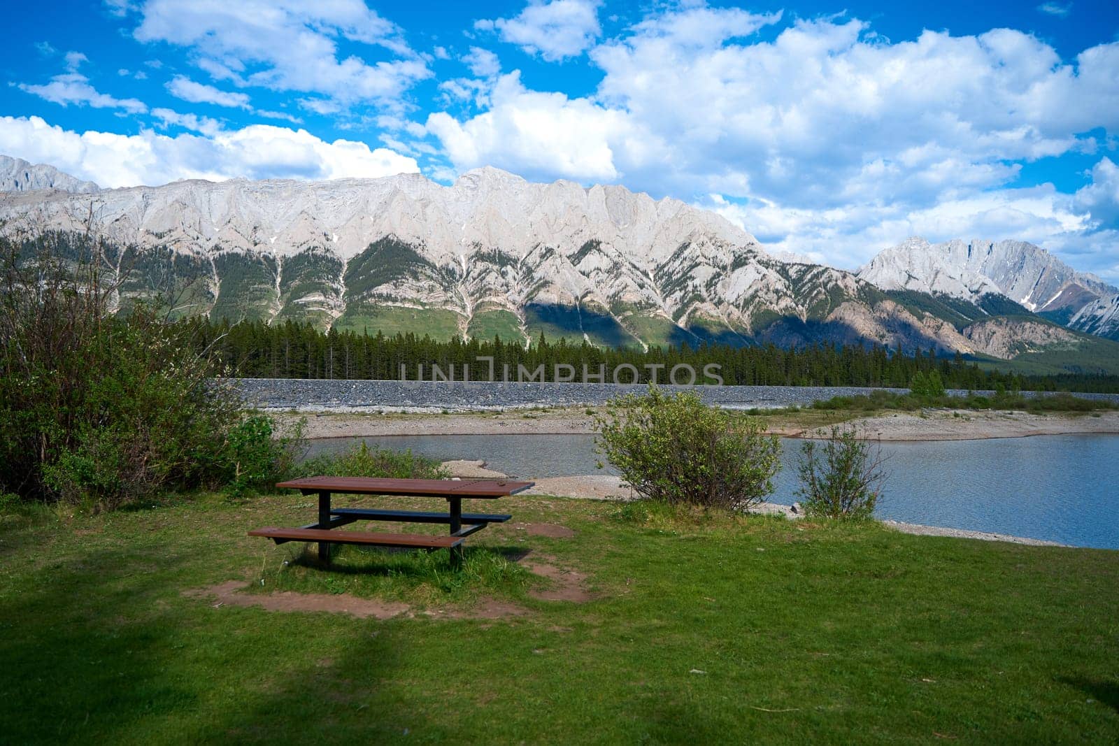A picnic table on the edge of a lake overlooking the Canadian mountains in Alberta