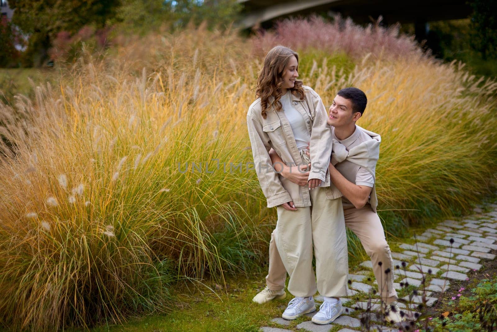 Young Cute Female Hugs Boyfriend. In Autumn Outdoor. Lovers Walking in Park. Attractive Funny Couple. Lovestory in Forest. Man and Woman. Cute Lovers in the Park. Family Concept. Happy Couple.