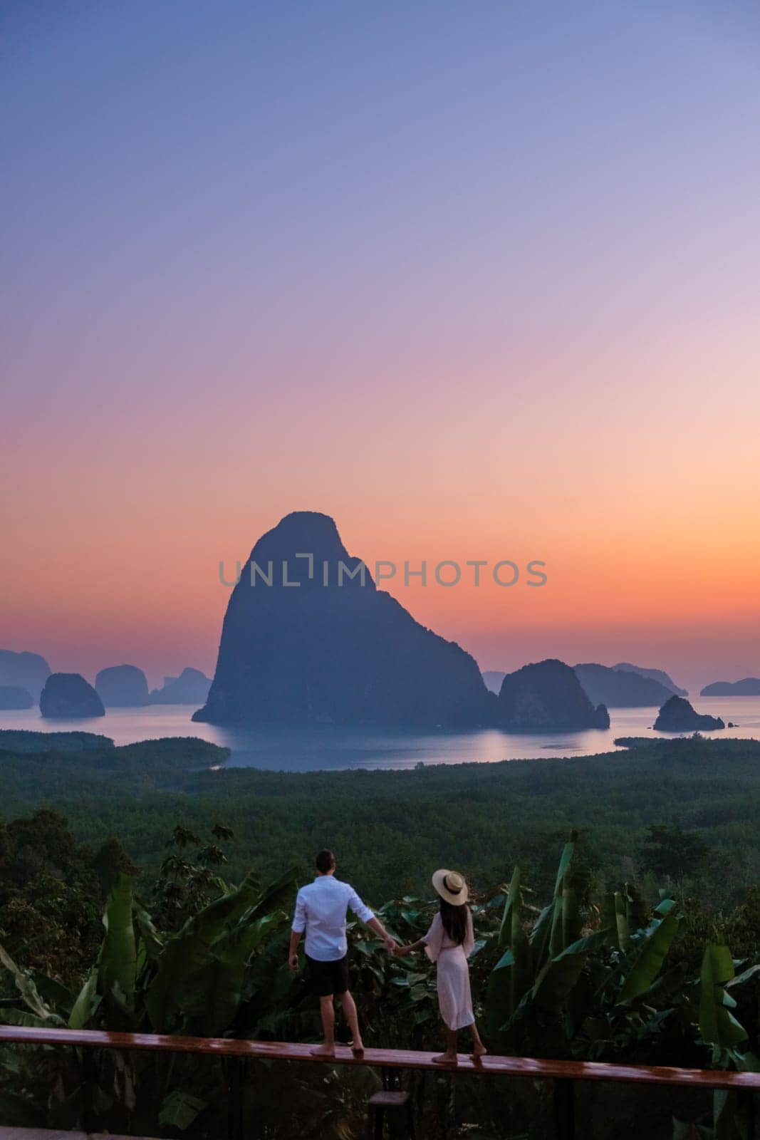 A couple of men and woman watching the sunrise at Sametnangshe viewpoint in Phangnga Bay with mangrove forest and limestone cliffs in the Andaman Sea, Sametnangshe Phangnga Thailand