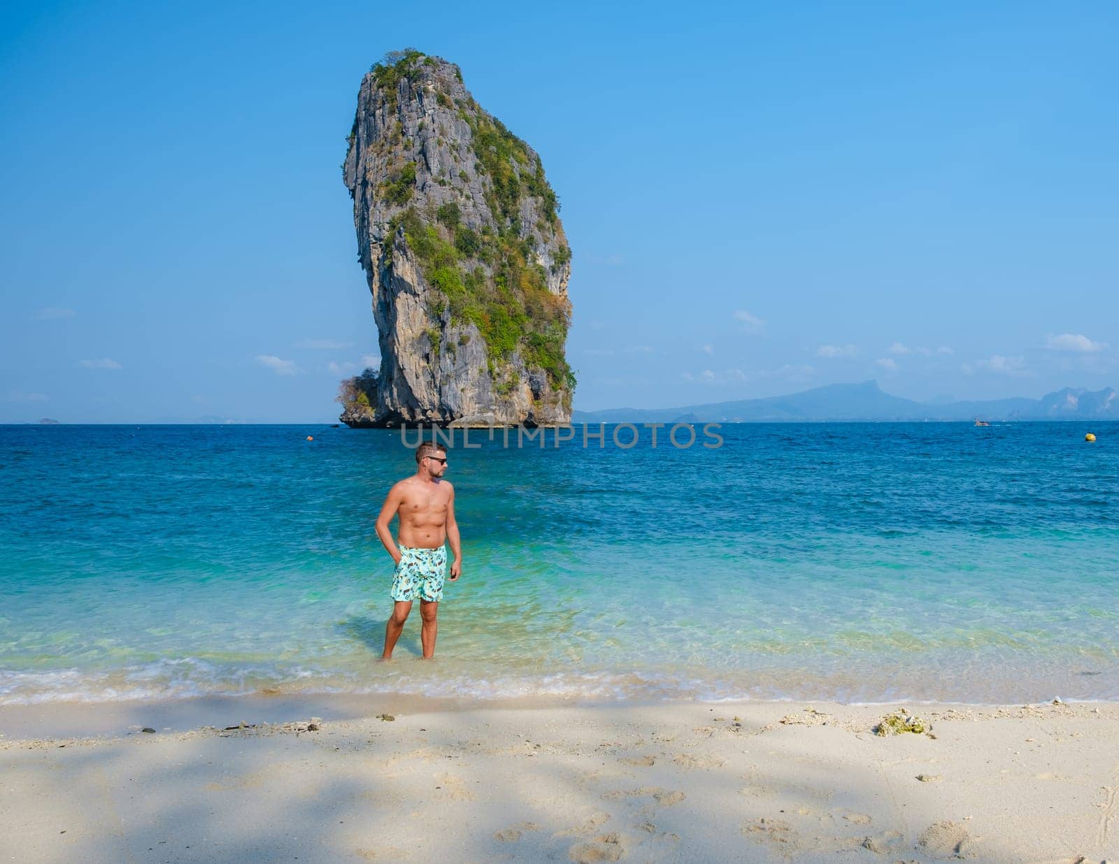 young men at Koh Poda Beach Krabi Thailand, the tropical beach of Koh Poda Island Krabi, a man in swim short walking on the beach,