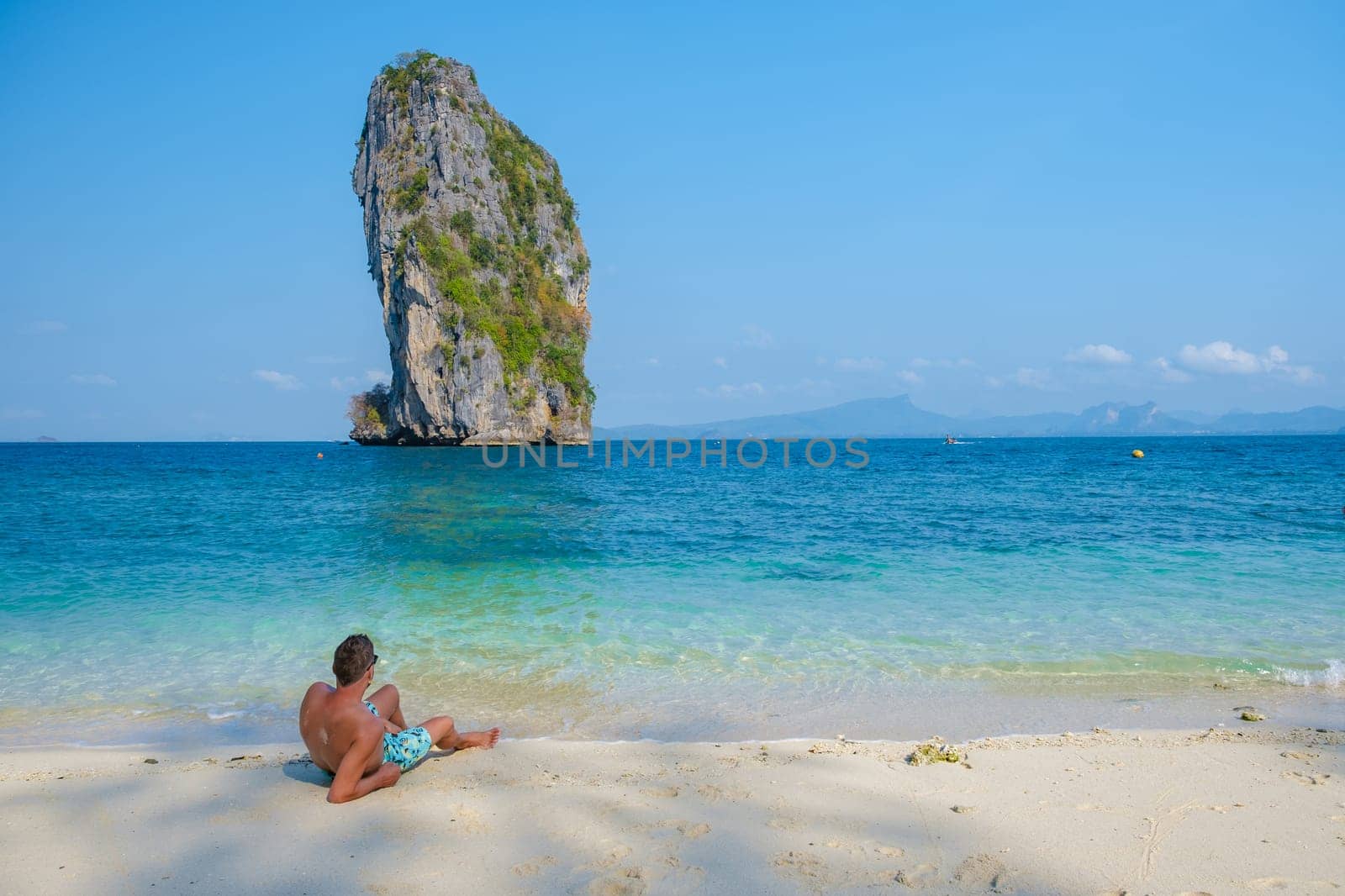 young men at Koh Poda Beach Krabi Thailand, the tropical beach of Koh Poda Island Krabi, a man in swim short lying down on the beach,