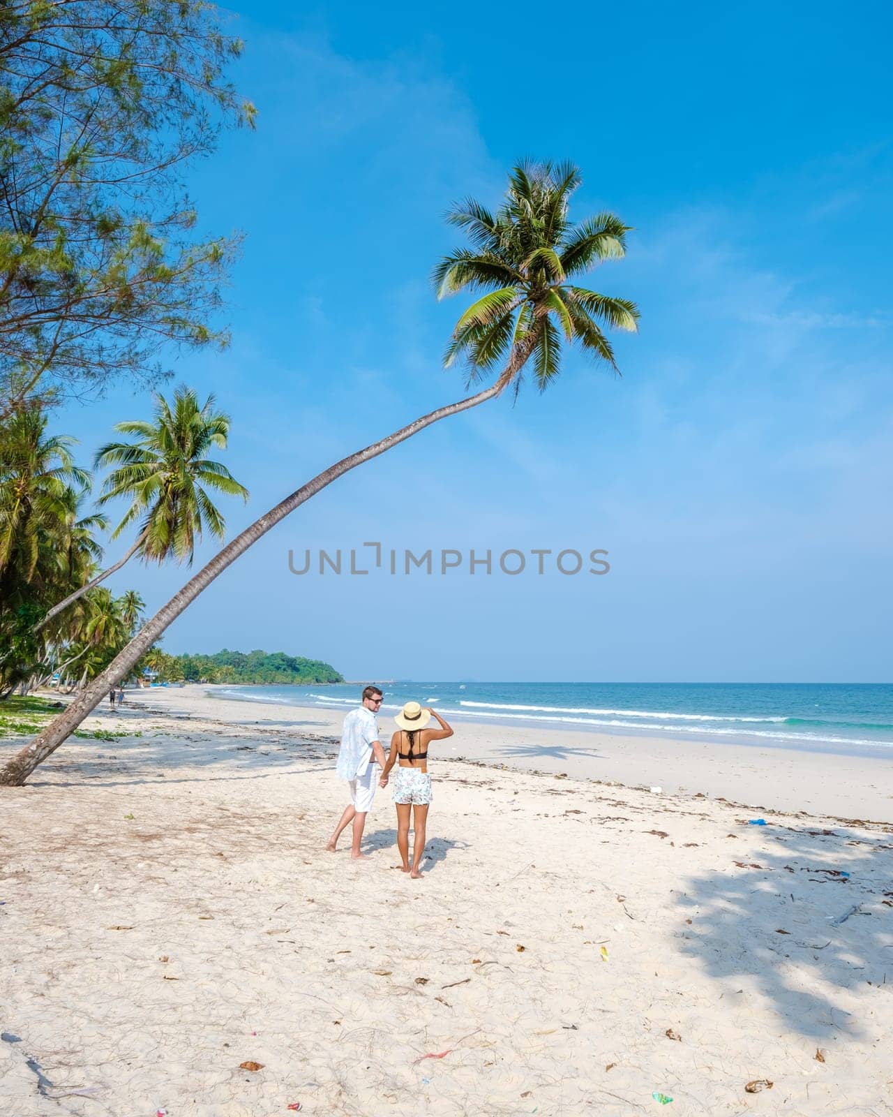 couple on vacation in Thailand, Chumphon province, white tropical beach with palm trees, Wua Laen beach Chumphon area Thailand, palm tree hanging over the beach with a couple on vacation in Thailand.