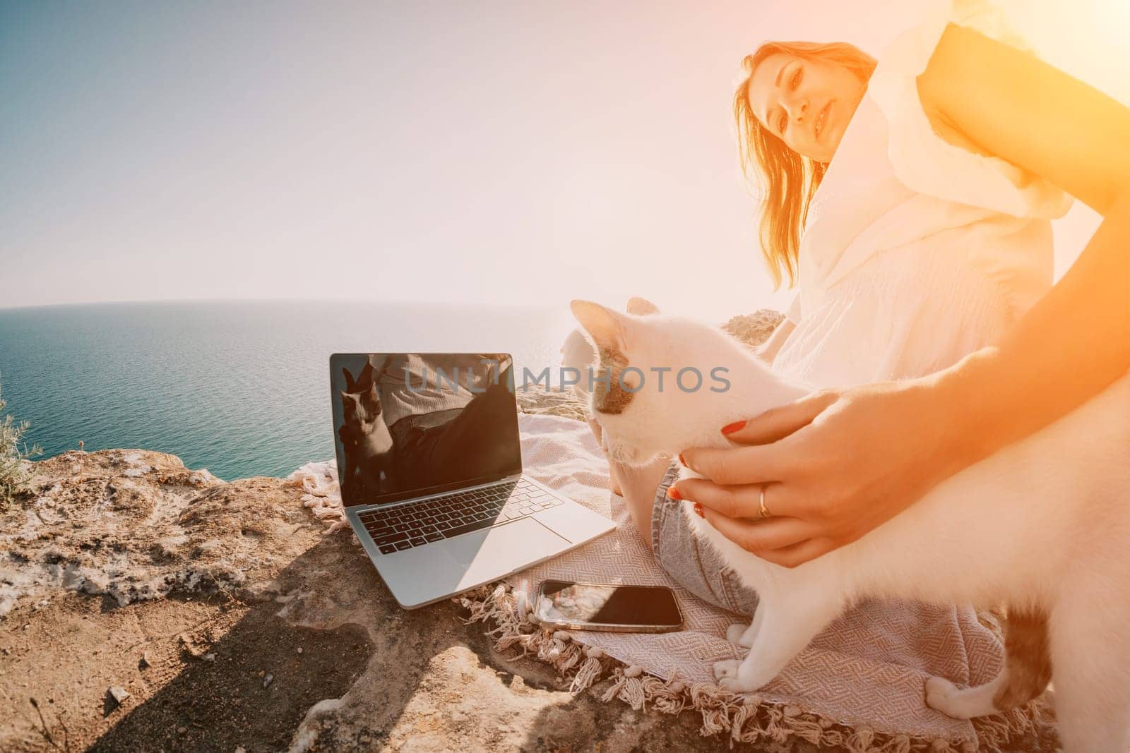 Woman sea laptop. Business woman petting cat and working on laptop by the sea. Close up on hands of pretty lady typing on computer outdoors summer day. Freelance, digital nomad and holidays concept. by panophotograph