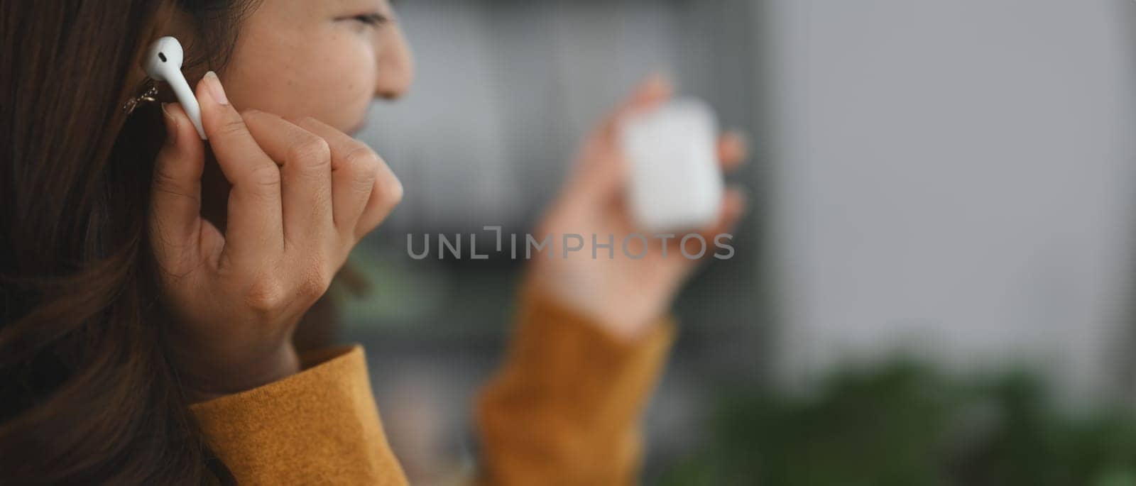 Cheerful woman enjoying music on wireless earphones, switching songs or changing the volume with her finger. by prathanchorruangsak