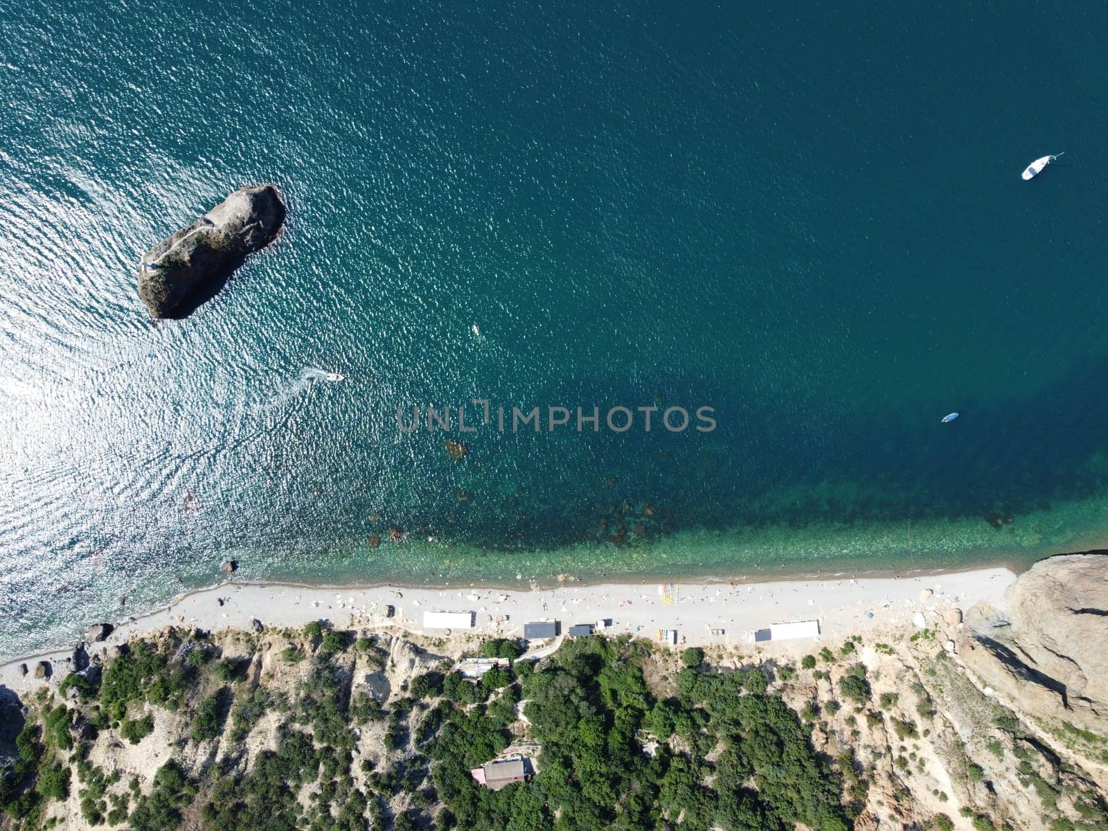 Aerial view from above on calm azure sea and volcanic rocky shores. Small waves on water surface in motion blur. Nature summer ocean sea beach background. Nobody. Holiday, vacation and travel concept by panophotograph