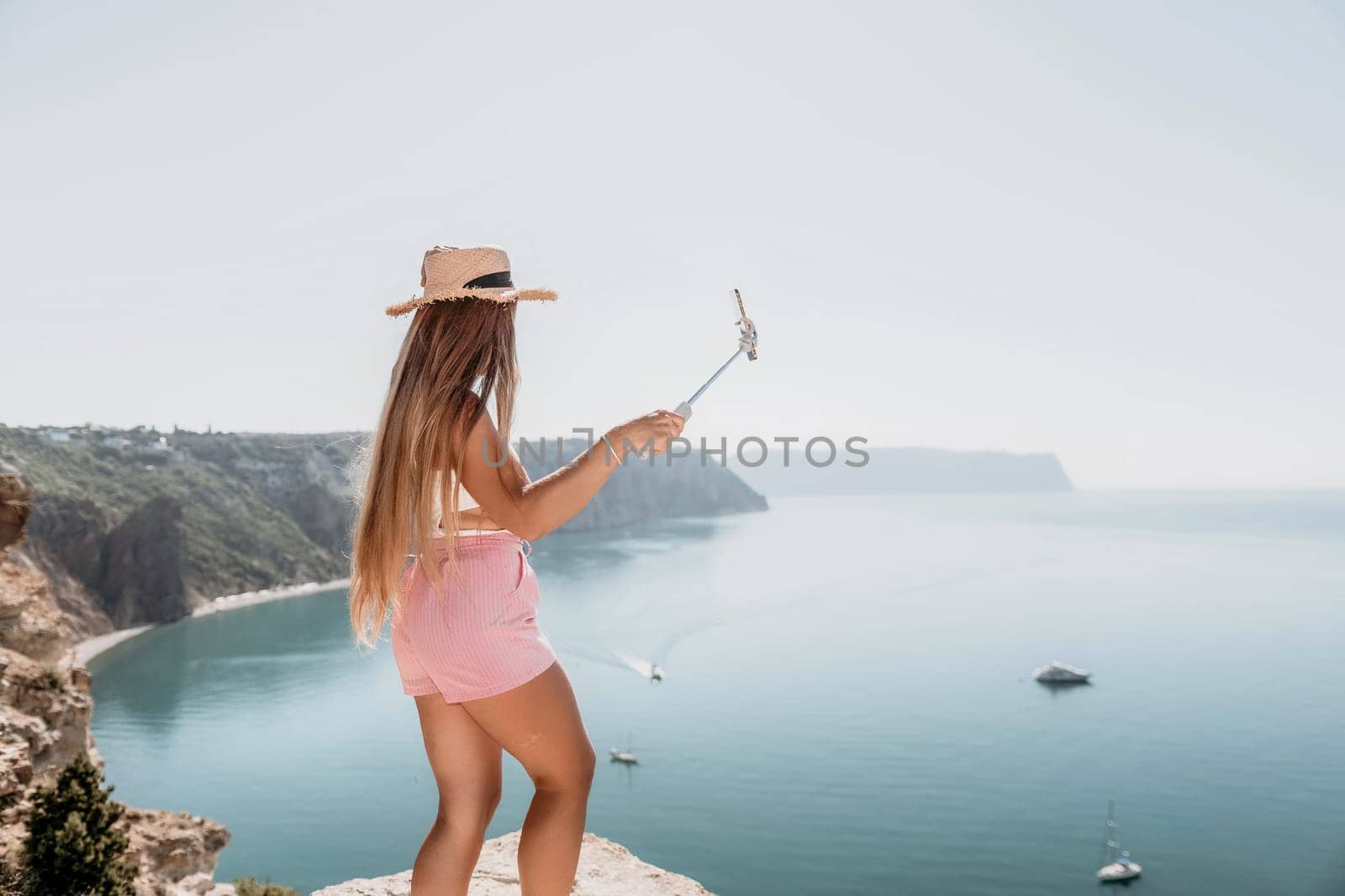 Woman sea laptop. Business woman in yellow hat freelancer with laptop working over blue sea beach. Girl relieves stress from work. Freelance, digital nomad, travel and holidays concept by panophotograph