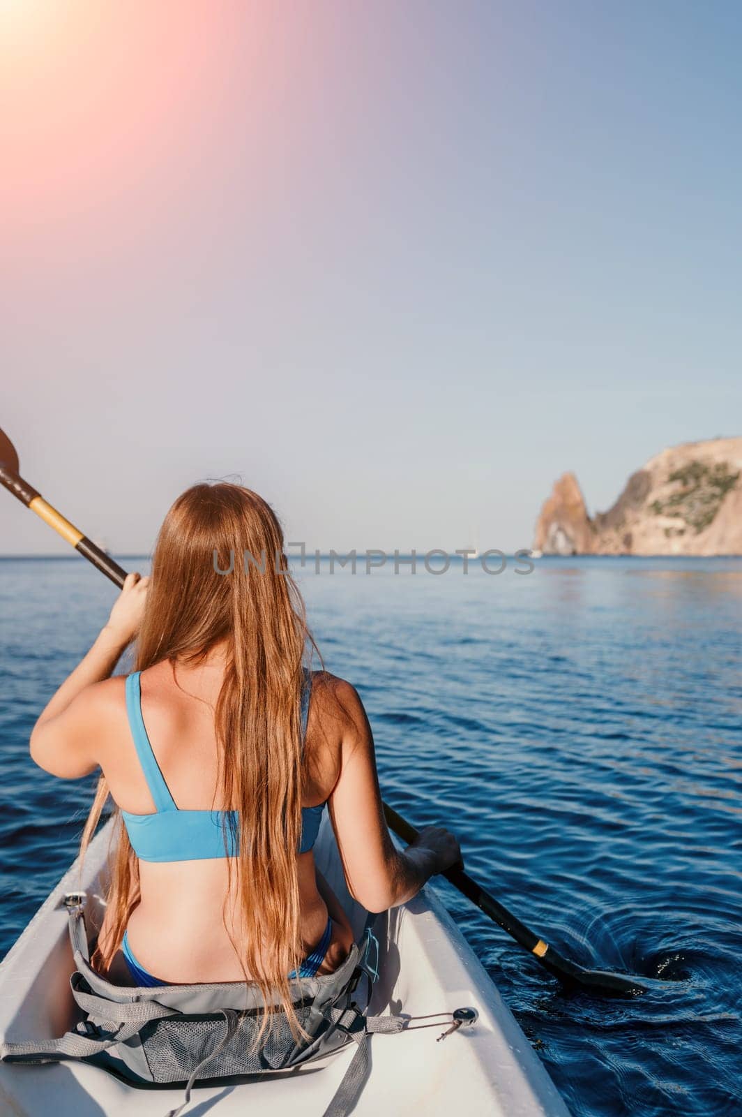 Woman in kayak back view. Happy young woman with long hair floating in kayak on calm sea. Summer holiday vacation and cheerful female people relaxing having fun on the boat. by panophotograph