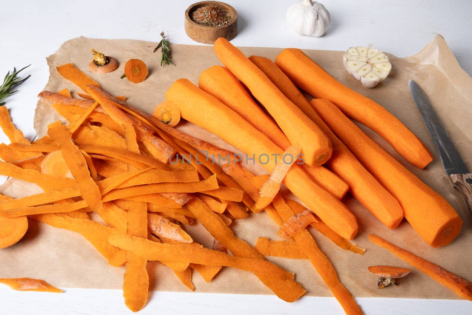 Peeled fresh raw carrots lie on parchment paper on the kitchen table. by OlgaGubskaya