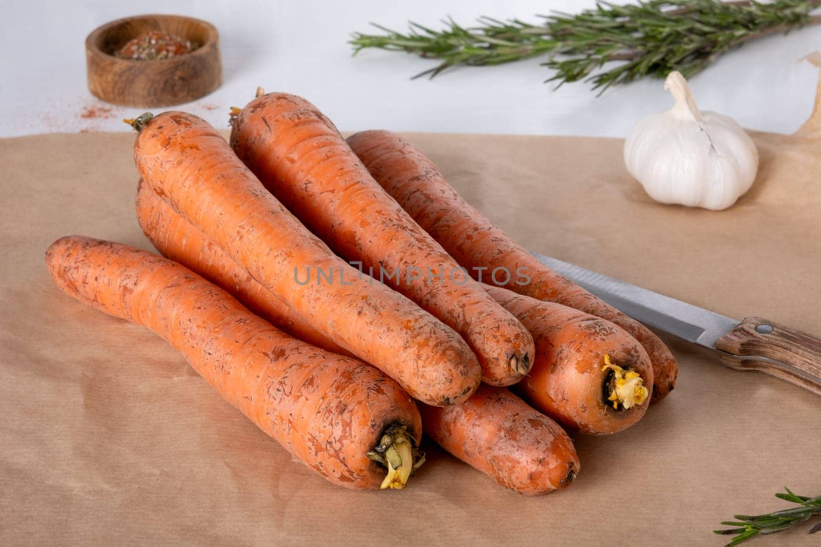 Fresh raw carrots lie on parchment paper on the kitchen table. Selective focus.