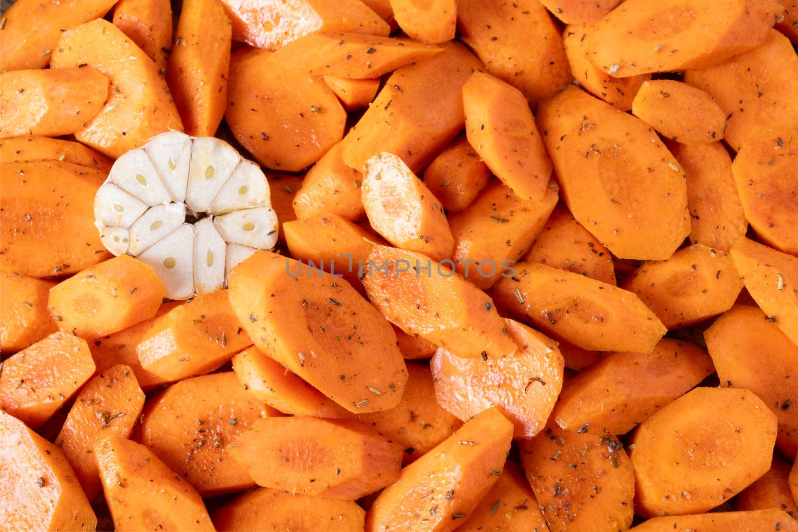 Fresh carrots cut into pieces, seasoned with spices and olive oil, lie on baking tray. Food background. Selective focus.