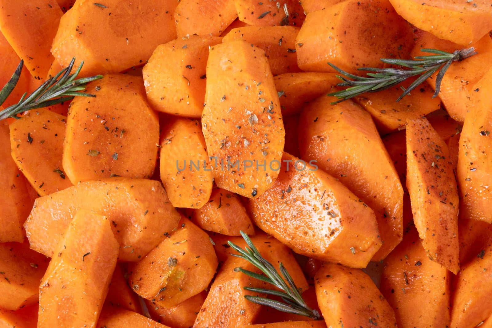 Carrots cut into pieces, seasoned with spices and olive oil, lie on baking tray. by OlgaGubskaya