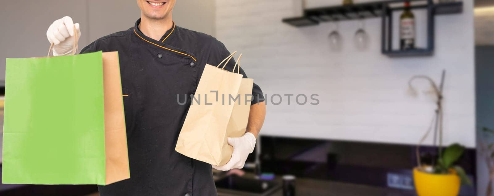 Paper pocket and food containers in hands of a smiling deliveryman. .Quality service of a restaurant