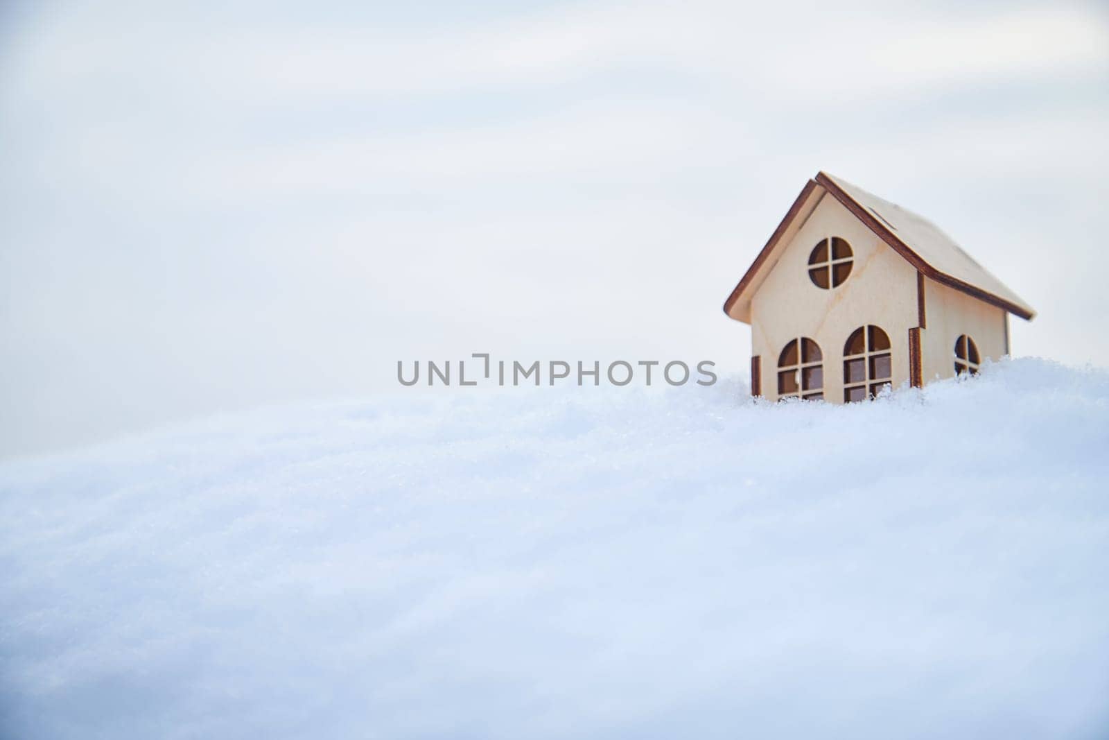 Wooden toy house on snow, natural abstract background. winter season concept. symbol of cozy, loving family home. construction, sales, rental concept. Christmas and new year holidays. copy space