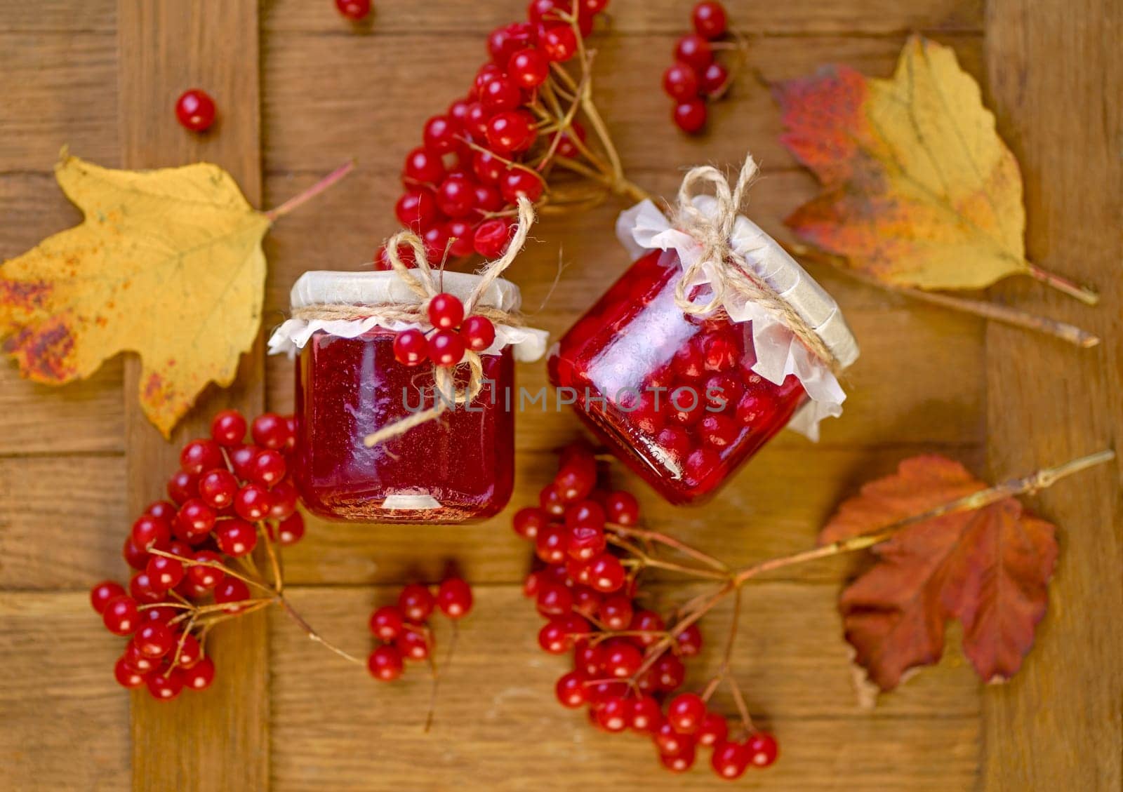 viburnum jam. Red juicy berries of a viburnum with sugar in a glass jar on a dark wooden background. For making jam, tea.