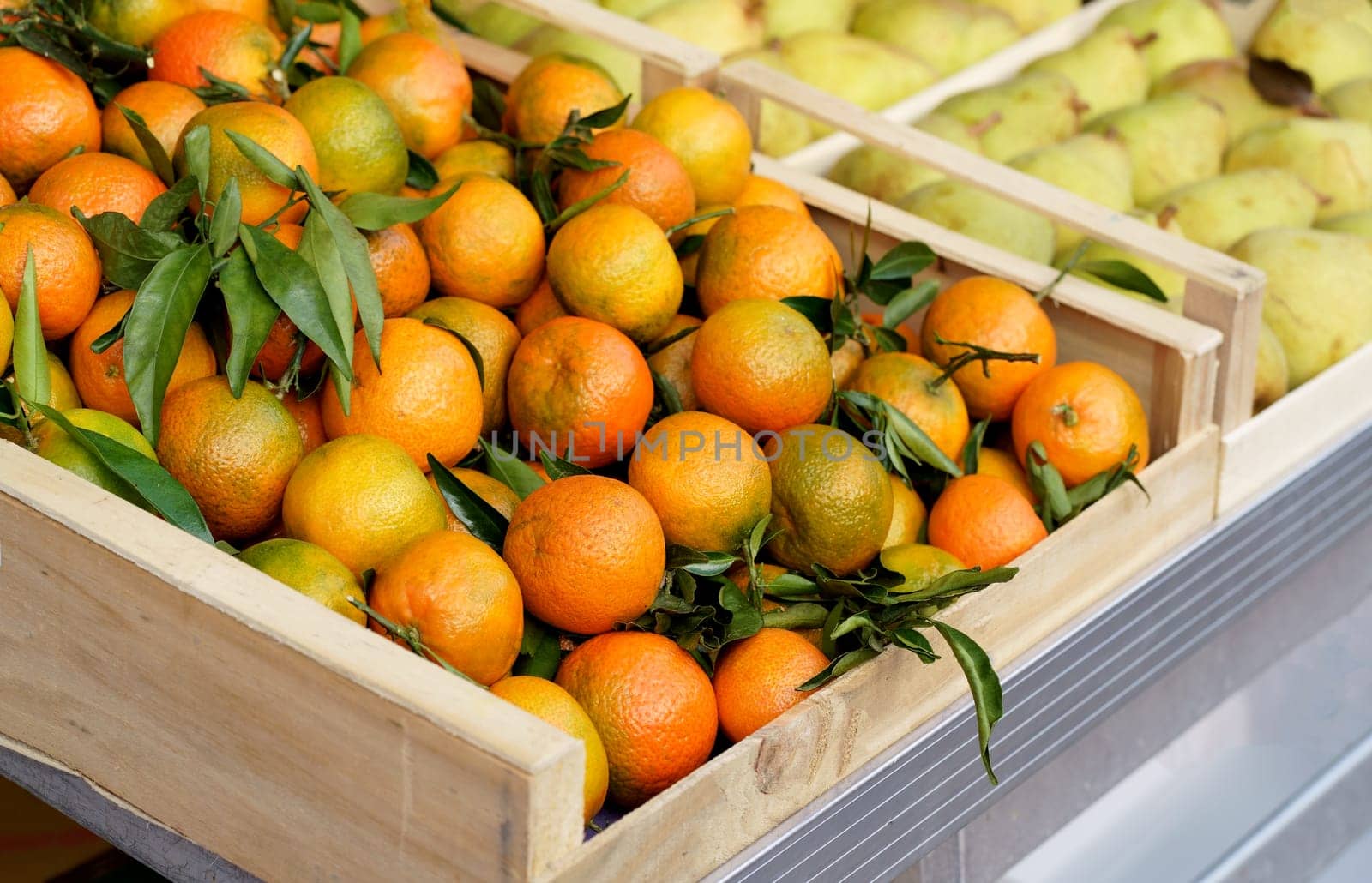 Boxes with tangerines. Fresh mandarin oranges or tangerines fruit with leaves in boxes at the open air local food market. Wholesale depot of exotic fruits.