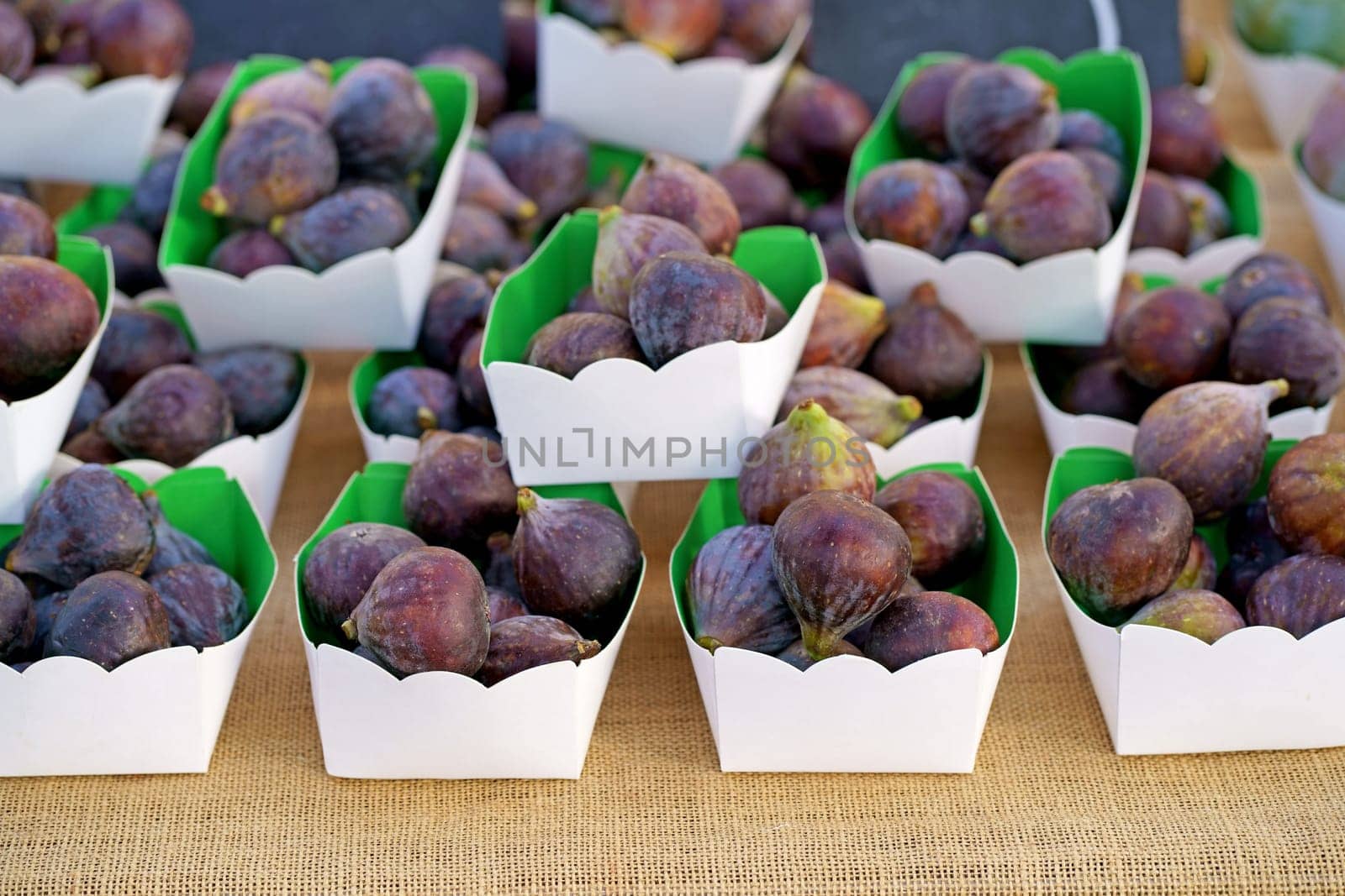 Fresh figs in a paper box. Fresh organic figs being sold on the table at a farmers market by aprilphoto