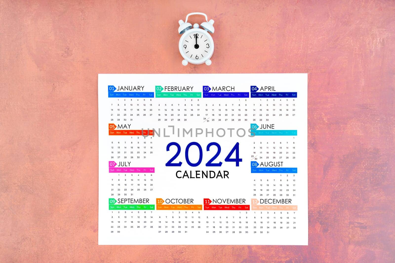 12 months desk calendar 2024 and alarm clock on old background.
