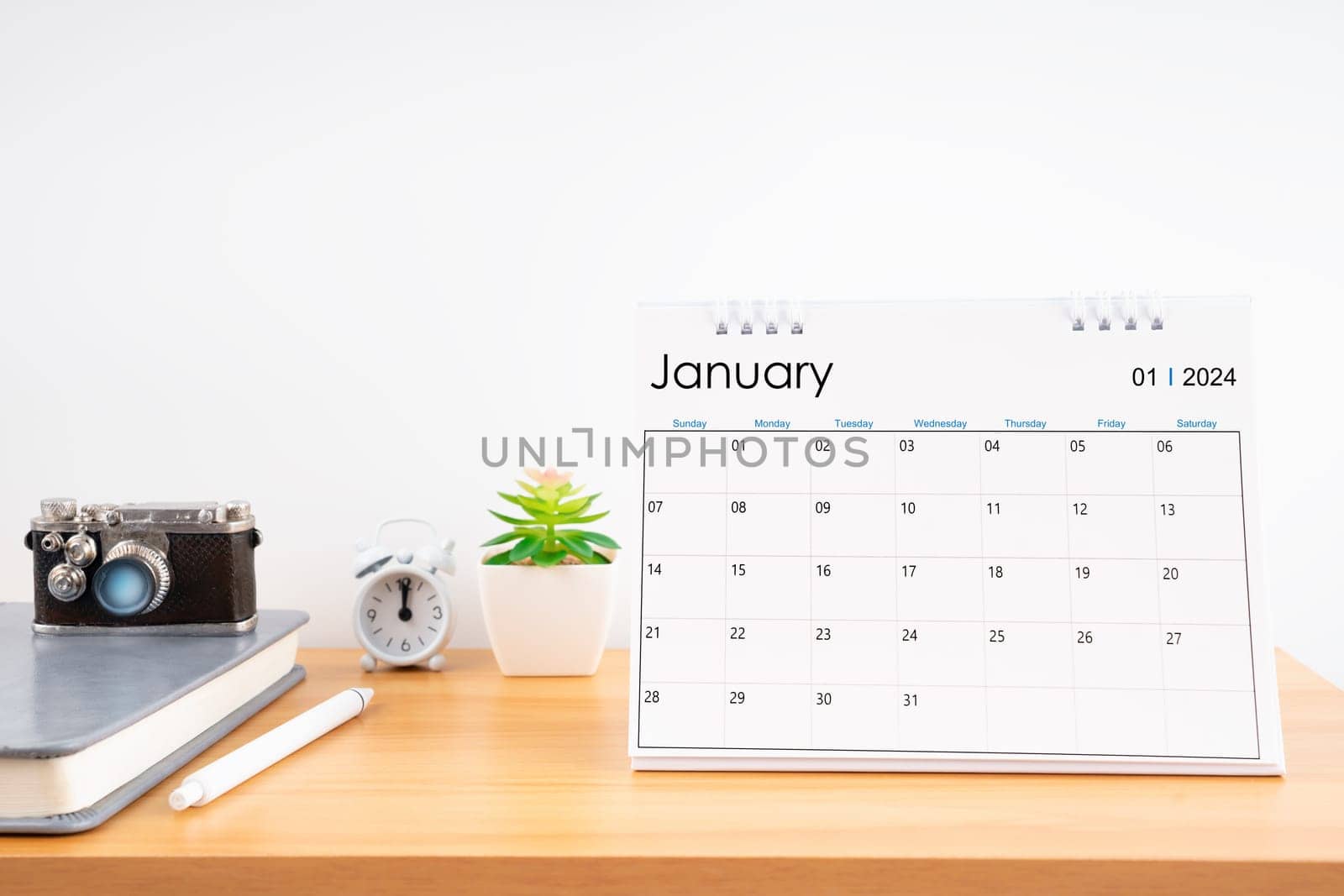 Desktop Calendar for January 2024 year and vintage camera with diary for Planner to plan timetable at Home Office.