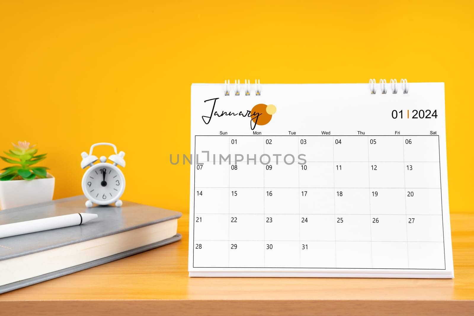 January desk calendar for 2024 year on work table with yellow background.