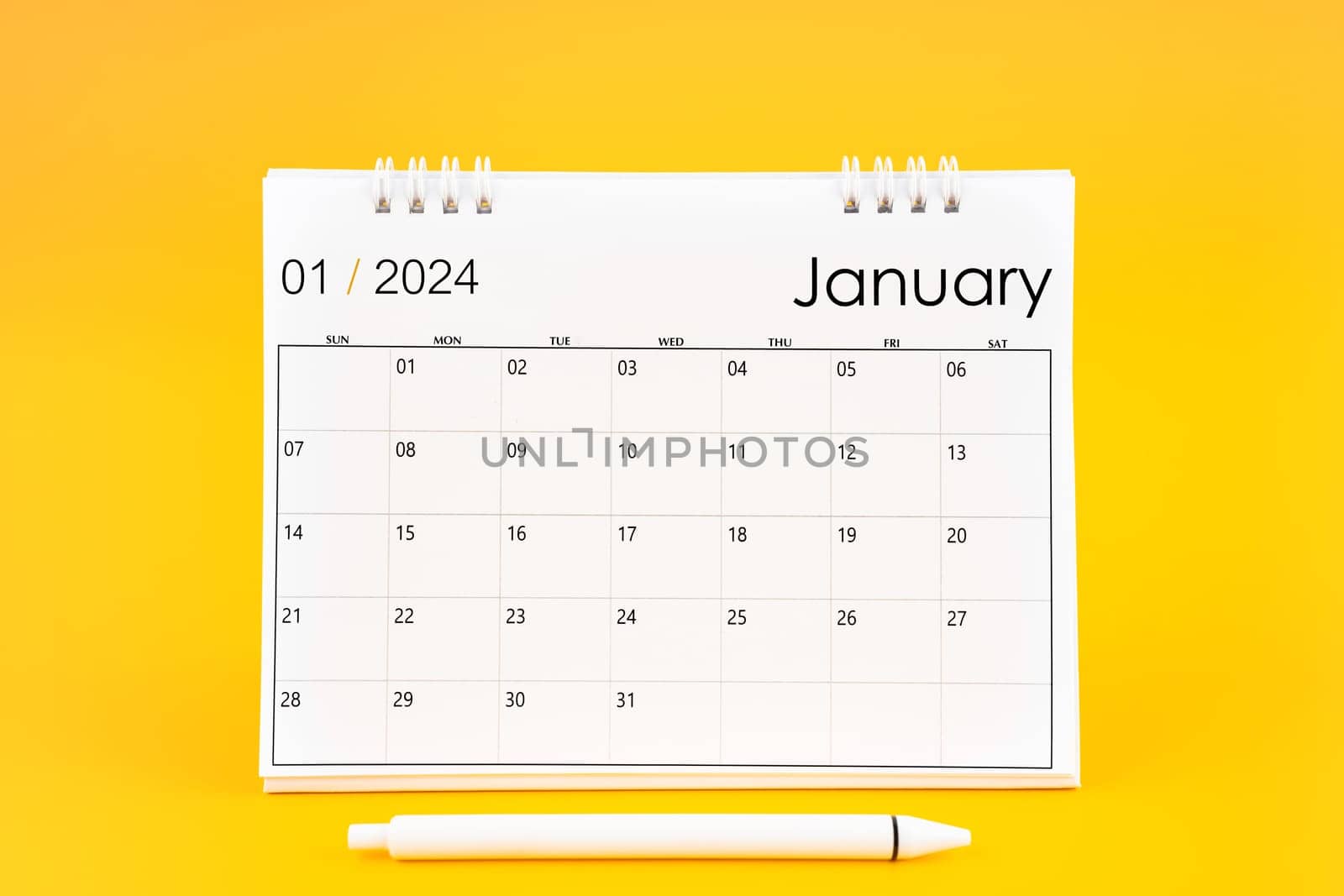 January 2024, Monthly desk calendar for 2024 year and pen on yellow color background.