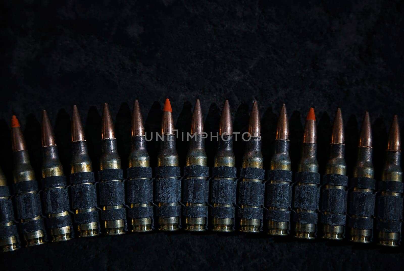 Machine gun bullet belt on the floor. Background on the military theme. Ammo, chain of ammo on concrete background. Top view of machine gun belt cartridge 7.62 mm caliber on dark background by EvgeniyQW